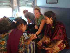 Donna getting a henna tattoo from two sisters while on a train